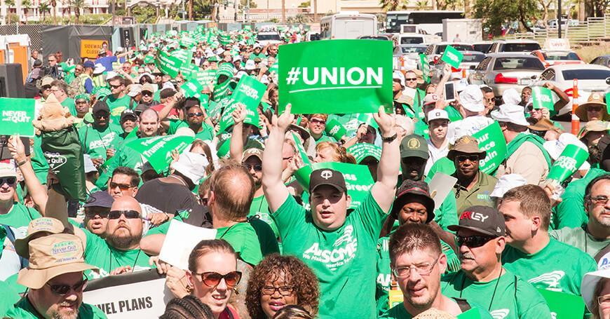 Crowd of men and women in green AFSCME t-shirts, one is holding a green sign that reads, "#UNION".