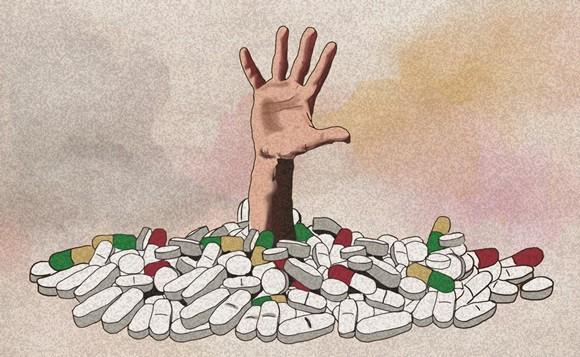 Hand reaching out of opioid pills
