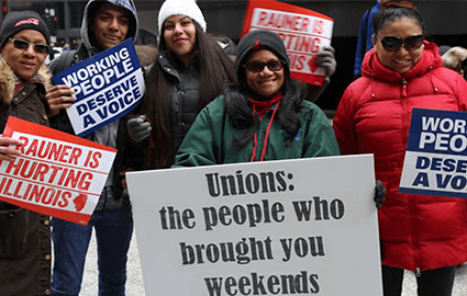 AFSCME members in Illinois rally with signs that say "Working people deserve a voice" and "Rauner is hurting Illinois."